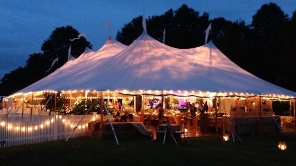 A sailcloth tent glowing at dusk, ready for an evening reception