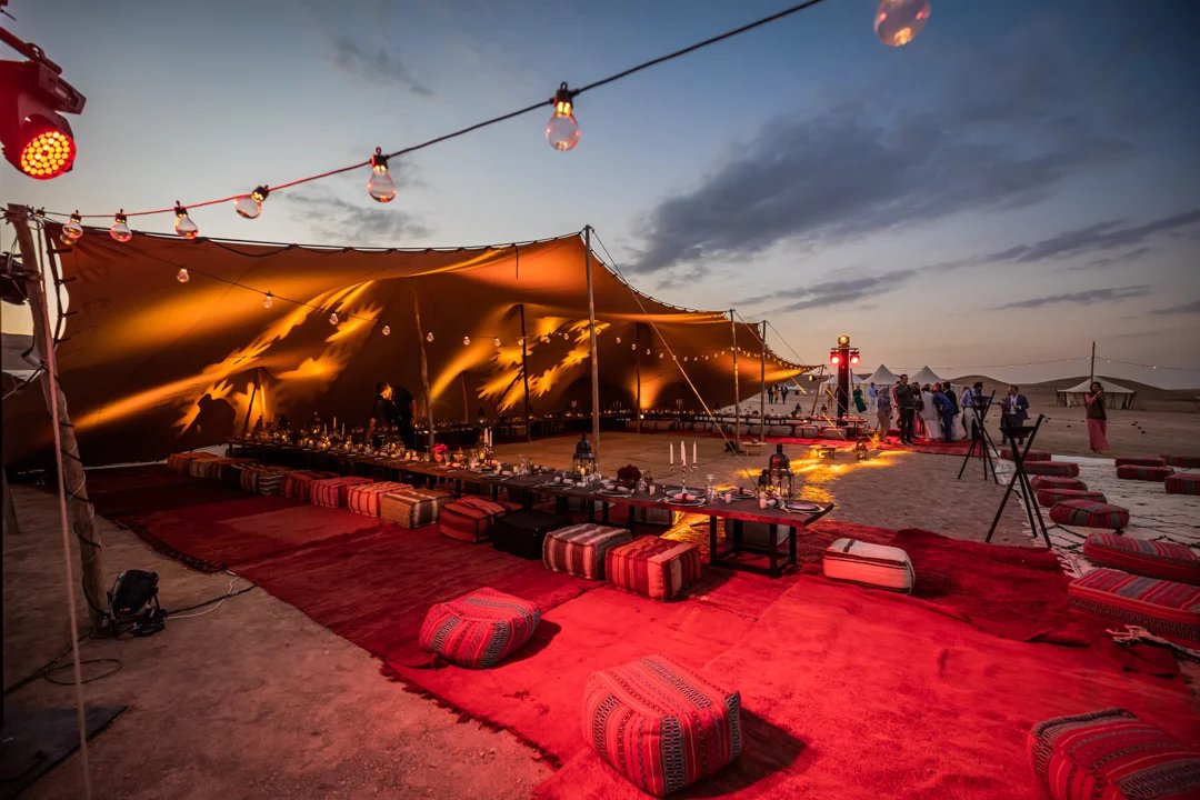 A glowing stretch canopy over a desert celebration at dusk